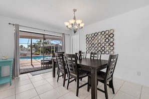 A dining area with a pool view, a chandelier, and a wall with circular decorations.