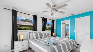 A bedroom with a bed, nightstands, a ceiling fan, and a view of the outside. - Turquoise Tides -Cape Coral (Cape Coral)