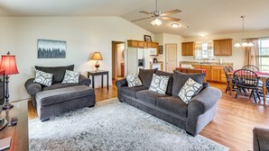 A spacious living room with a grey sofa set, a patterned rug, and a dining area with a wooden table and chairs. - 3 Mi to Arkansas River: Rural Family Home w/ Yard (Spiro)