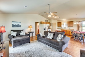A spacious living room with a grey sofa set, a patterned rug, and a dining area with a wooden table and chairs. - 3 Mi to Arkansas River: Rural Family Home w/ Yard (Spiro)