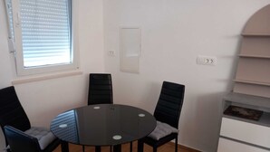 A round table with four chairs, a window with blinds, and a white cabinet with drawers.