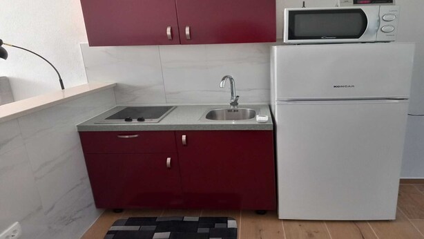 A compact kitchen with a microwave, sink, and refrigerator.