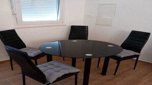 A room with a round glass table surrounded by four black chairs with grey cushions.