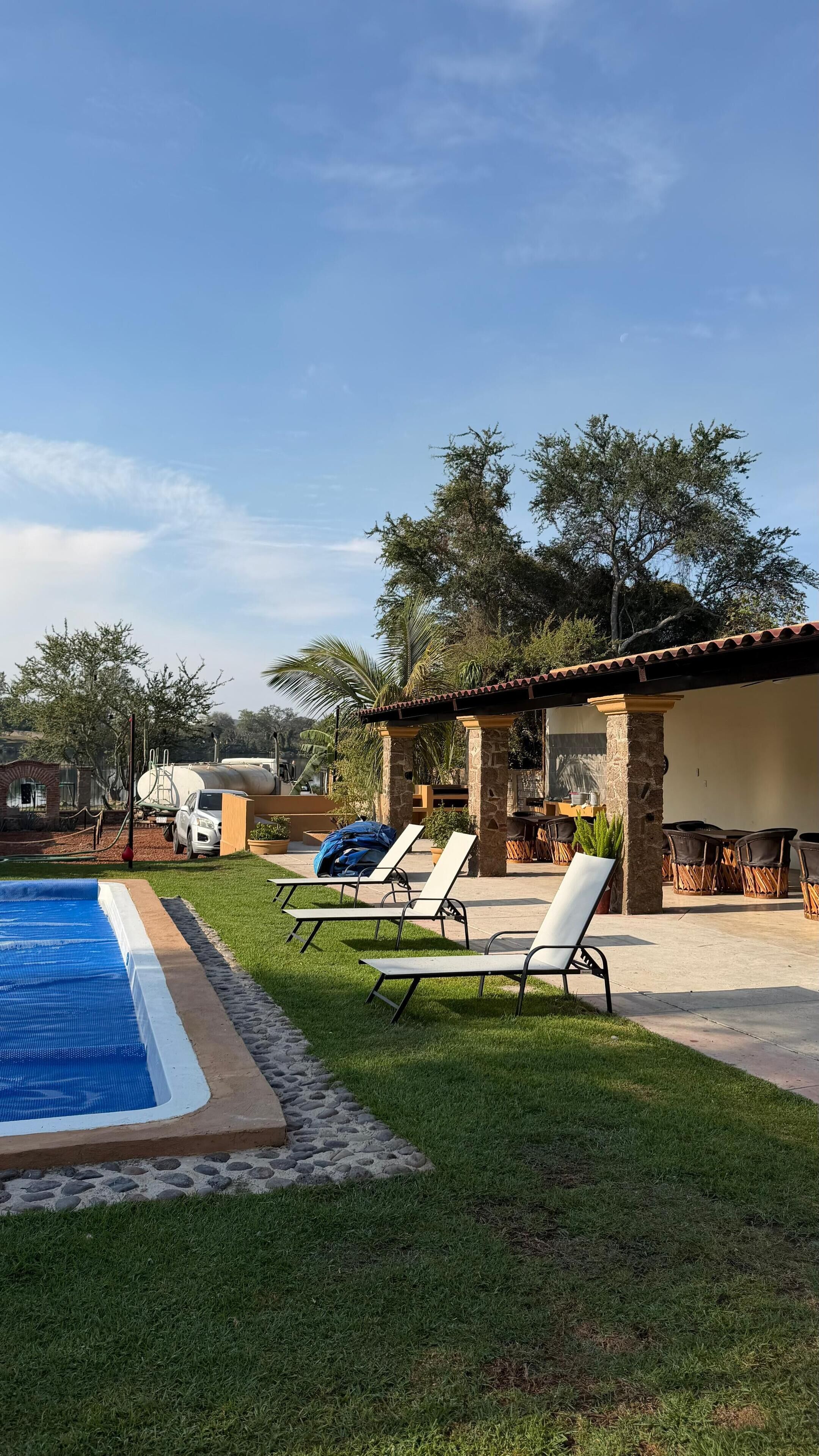 A backyard with a swimming pool, lounge chairs, and a pergola.