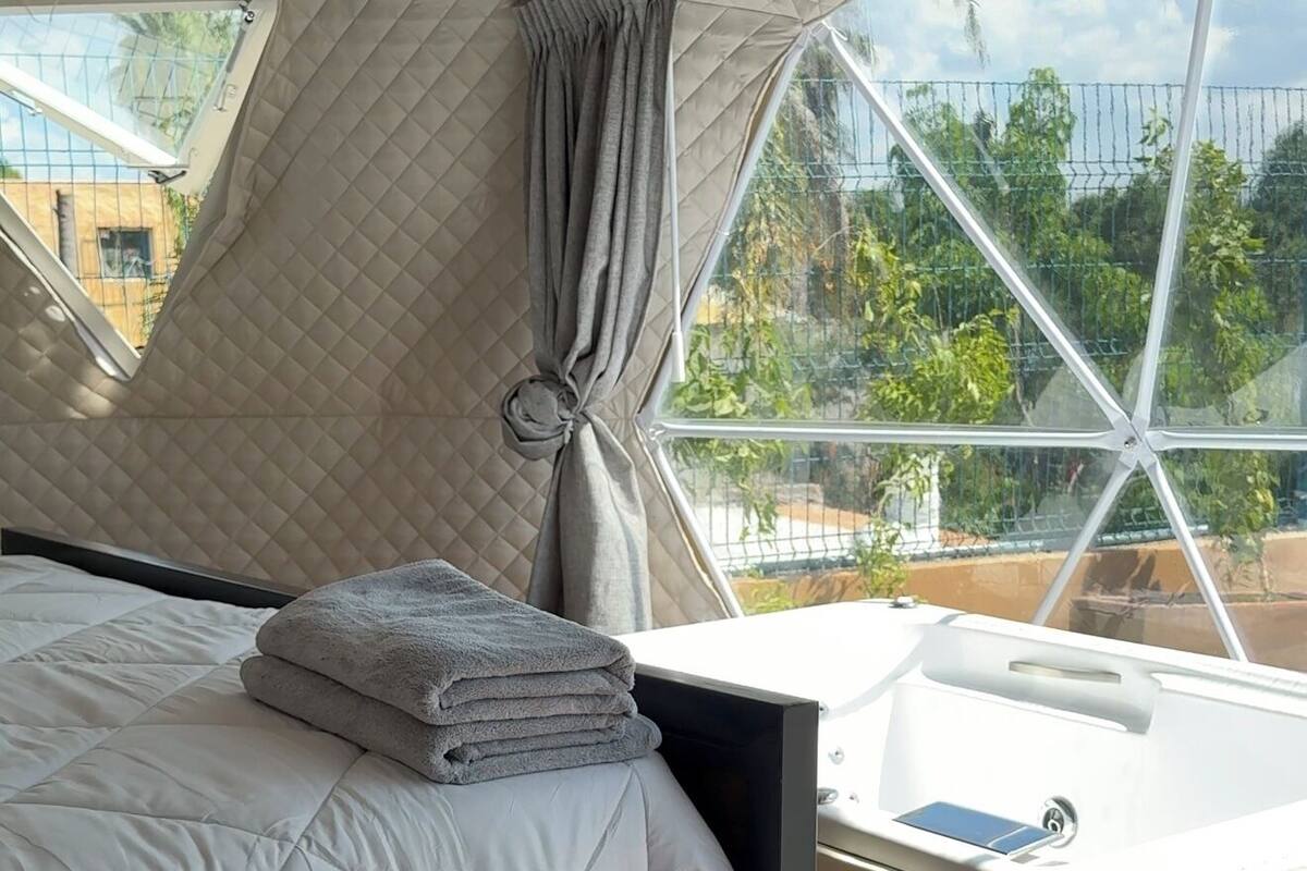 A bedroom with a bed, a window, and a bathtub.