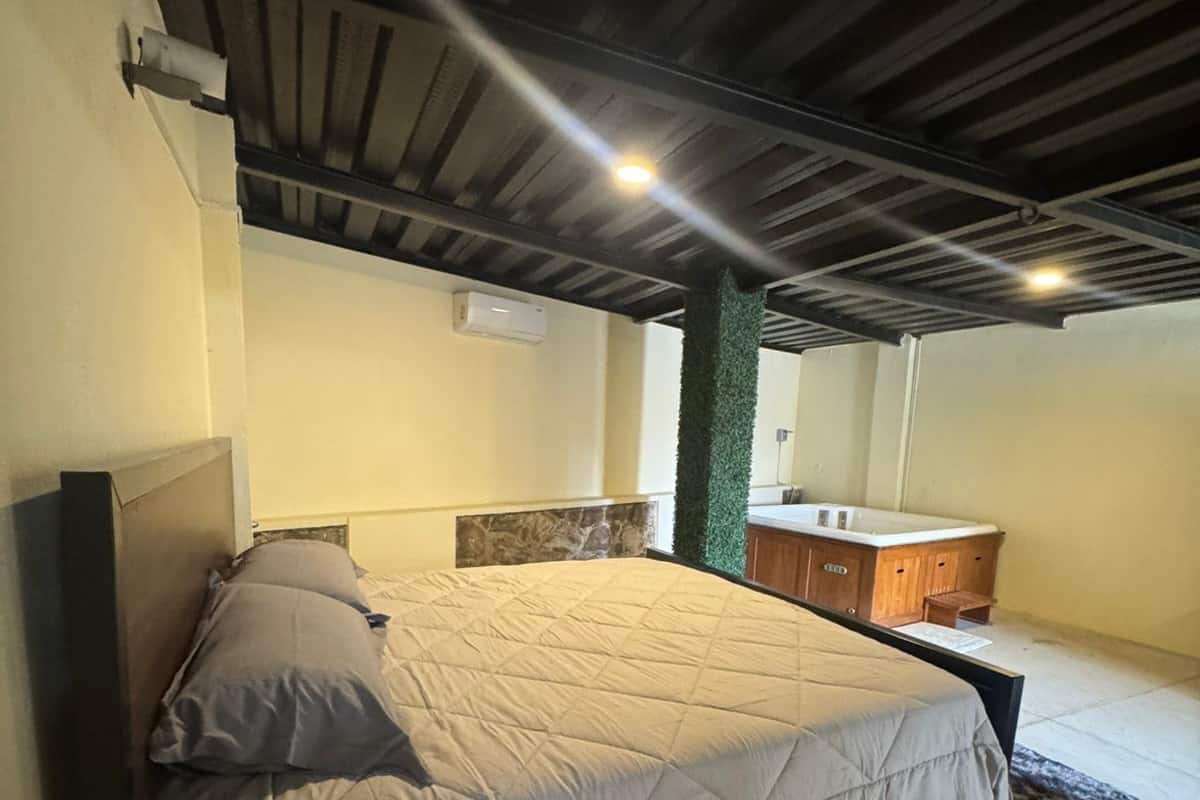 A bedroom with a bed, a wooden headboard, a green wall, a wooden cabinet, and a window.
