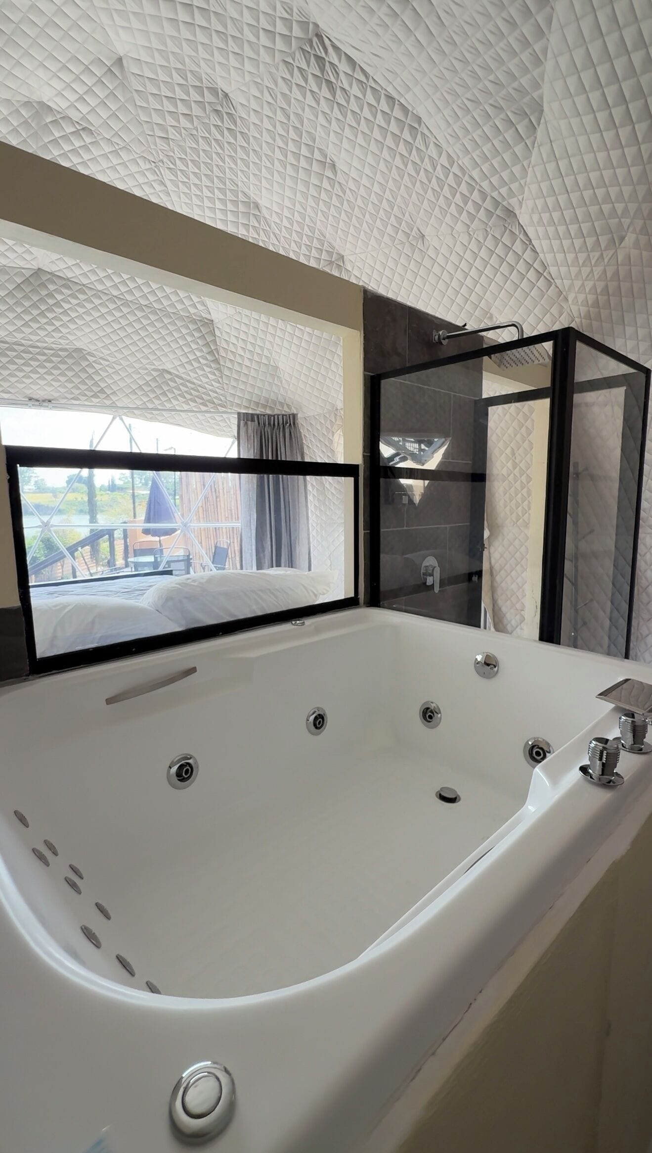 Un bagno moderno con una grande vasca, uno spazio doccia in vetro e vista sull'esterno da una finestra.