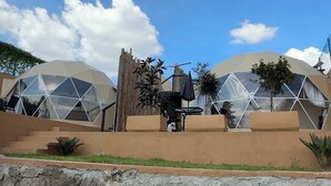 Una serie de estructuras en forma de domos geodésicos con un muro de piedra al frente.