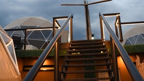 Una escalera conduce a un edificio de diseño moderno, con patrones geométricos en las paredes y vistas al cielo.
