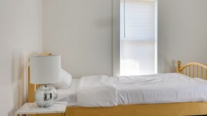 Une chambre à coucher avec un lit, une table de chevet avec une lampe et une fenêtre avec des stores.
