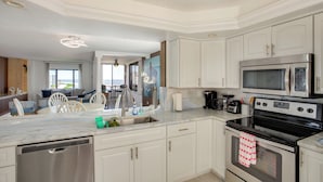 Una cocina moderna con armarios blancos, electrodomésticos de acero inoxidable y vistas al área de estar.
