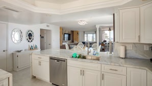 Una cocina moderna con armarios blancos, lavavajillas y encimera de mármol.