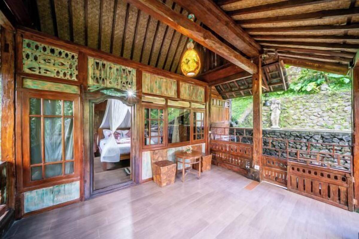 A rustic wooden room with a bed, a small table, and a stone wall.