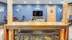 Angolo con bancone in legno, TV, sedie di legno e un cartello con la scritta 'WHITECAP MOUNTAINS'.