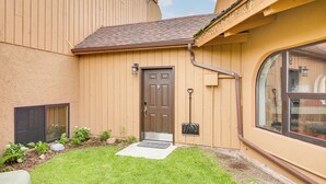 Una casa con una porta marrone, un piccolo giardino e una finestra.