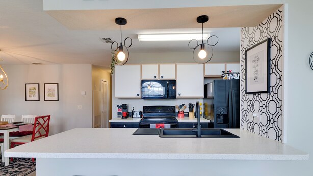 A modern kitchen with a central island, pendant lighting, and a patterned backsplash. - 5 Mi to WDW: Resort-Style Condo w/ Pool Access (Kissimmee)
