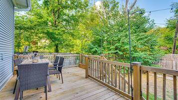 Une terrasse en bois, agrémentée de mobilier d’extérieur, entourée d’une clôture en bois et d’arbres.