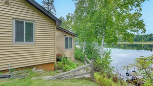 Una casa junto a un lago con una terraza de madera y una caña de pescar.