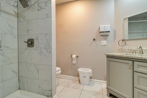 Ein Badezimmer mit Dusche, Toilette, Waschbecken und einem Mülleimer.