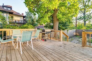 Eine Holzterrasse mit Gartenmöbeln und einem Grill.