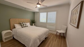 A bedroom with a bed, a ceiling fan, a window with blinds, a chair, and a wall-mounted picture. - Sage at 80 Cooloola Drive - Rainbow Beach (Rainbow Beach)