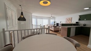 A modern kitchen with a dining area, a staircase, and a living room with a sofa and TV. - Sage - Rainbow Beach (Rainbow Beach)