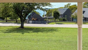 Un barrio residencial con un césped cuidado, un árbol grande y casas de techos oscuros y paredes de piedra.