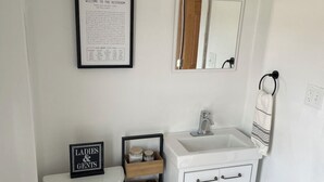 Een badkamer met toilet, wastafel en een lijst met een kruiswoordraadsel.