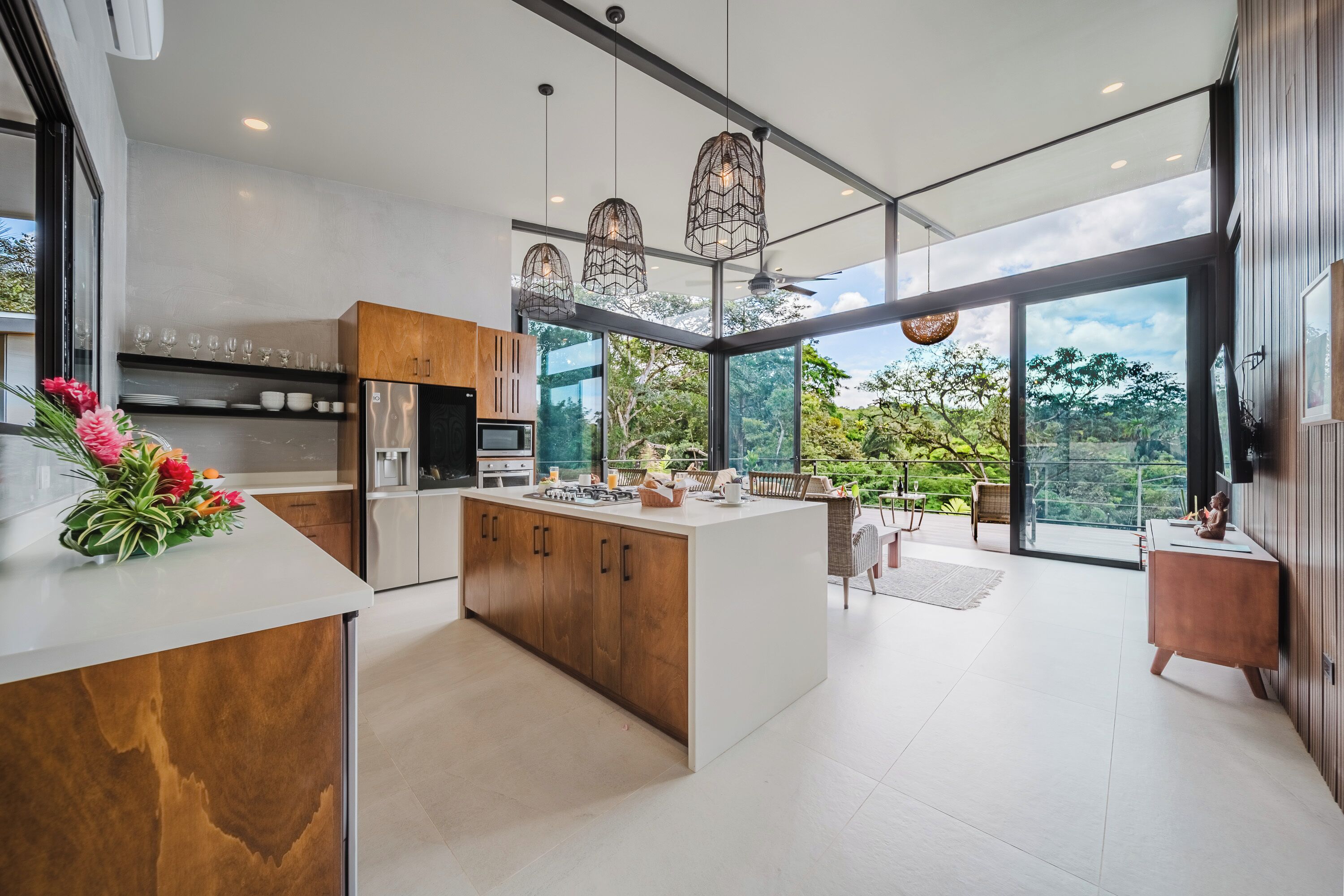 A modern kitchen with a central island, large windows, and hanging pendant lights.