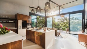 A modern kitchen with a central island, wooden cabinets, and a large window offering a view of the outdoors. - Wonderful 2-bedroom house with AC and private pool in Quepos (Quepos)