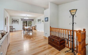 Un vaste salon doté d’un plancher en bois, un coin repas avec une table et des chaises, et un escalier agrémenté d’une lampe décorative.