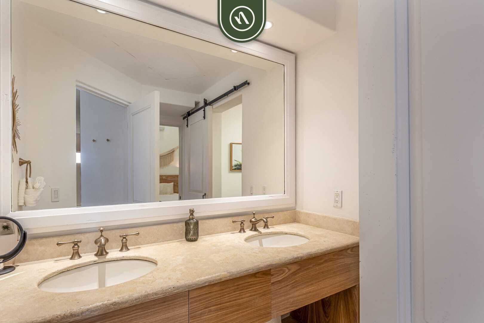 Une salle de bain avec deux lavabos, un grand miroir et un porte-serviettes.