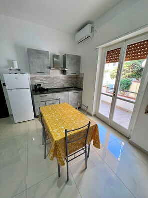 Una cocina compacta con una mesa de comedor, un refrigerador y un equipo de aire acondicionado.