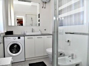 A modern bathroom with a washing machine, a sink, a toilet, and a glass shower enclosure. - Apartments Near Sea Supetar (Supetar)