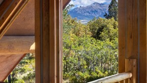 Un balcón de madera con vistas a una montaña y un bosque denso.