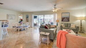 A spacious living room with a dining area, a sofa, and a coffee table. - Hot Tub + Heated Pool, Gulf Access, Waterfront with Lanai TV (Cape Coral)