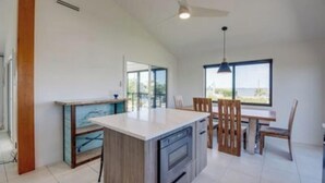 Een moderne keuken met een centraal eiland, houten kastjes en een eethoek met een tafel en stoelen.