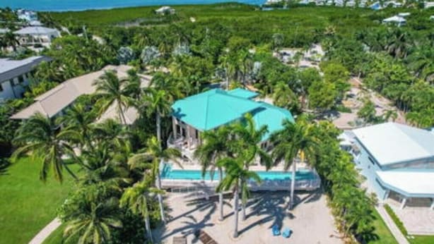 Un resort con piscina, palmeras y vista al océano.
