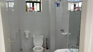 Une salle de bain équipée de toilettes, d’un lavabo, d’une douche et d’une fenêtre.