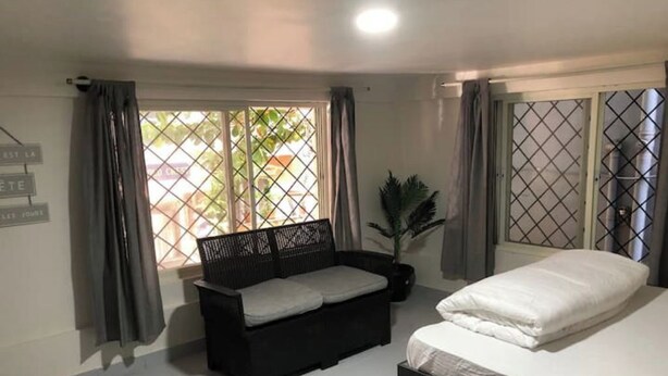 Un dormitorio con cama, sofá y ventana con cortinas.