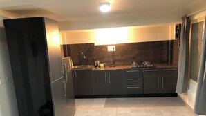 Una cocina moderna con armarios oscuros, una isla central y un horno empotrado.