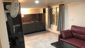 Un espacio habitable compacto con kitchenette, una zona de comedor con mesa y sofá.