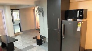 Una cocina compacta con refrigerador, microondas y una pequeña mesa.