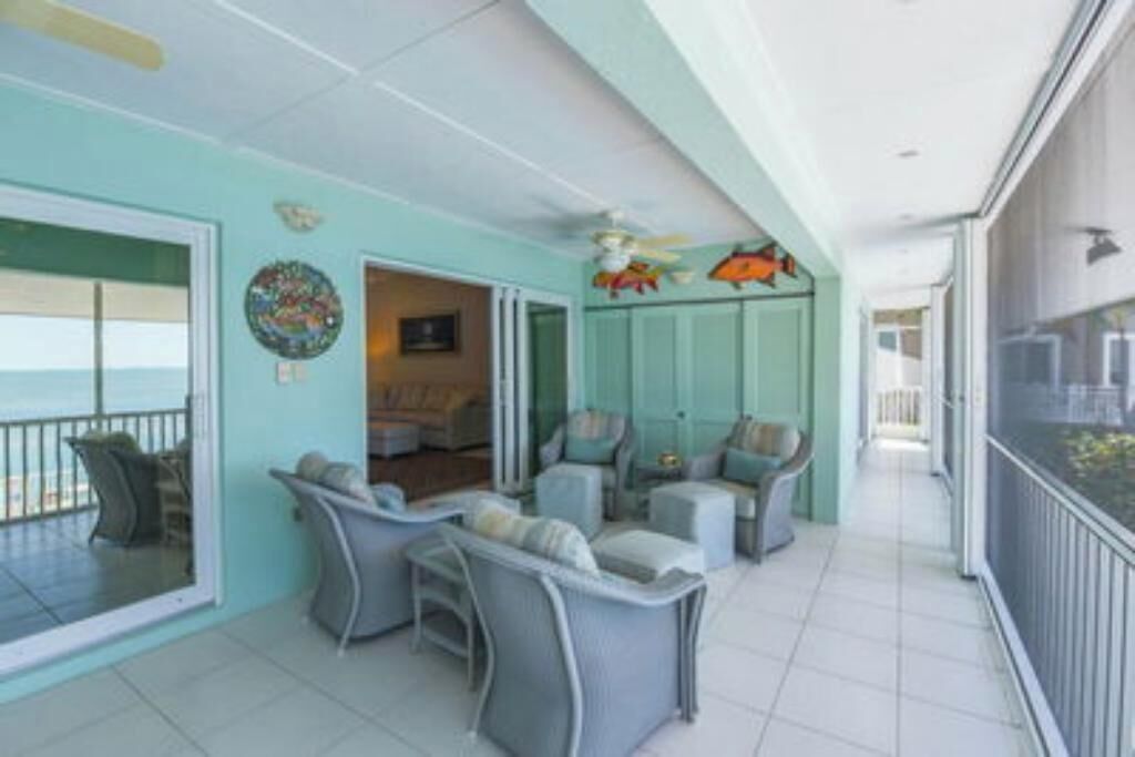 A spacious balcony with a view of the ocean, furnished with grey chairs and a small table.
