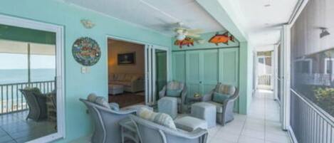 A spacious balcony with a view of the ocean, furnished with grey chairs and a small table.