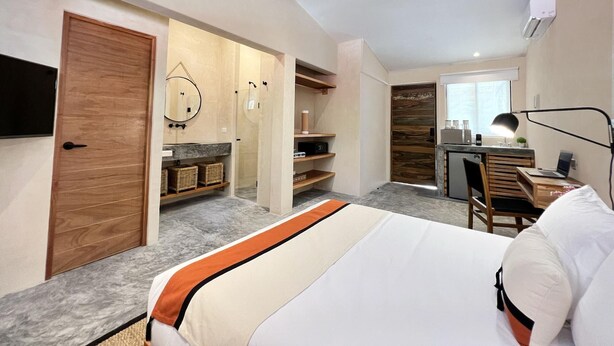 Un dormitorio moderno con una cama grande, un escritorio y un baño con espejo y estantes.