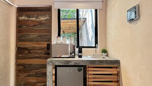 Un baño pequeño con puerta de madera, un lavamanos con espejo y un refrigerador compacto.