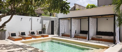 A poolside area with lounge chairs and a covered seating area.