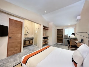 Un dormitorio moderno con una cama grande, un escritorio y un baño con espejo y estantes.