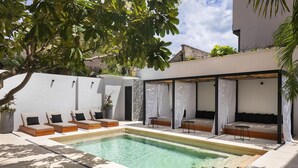 Zona de piscina con sillas de descanso y un área de estar techada.